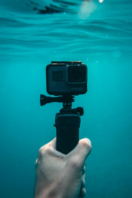 a person holding a camera in the water, a picture, gopro footage, undersea, action post, home video footage