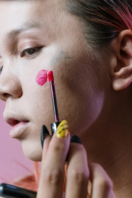 a woman putting lipstick on her face in front of a mirror, an album cover, inspired by Taro Yamamoto, trending on pexels, fluorescent pink face paint, close up face detail, portrait sophie mudd, pastel'