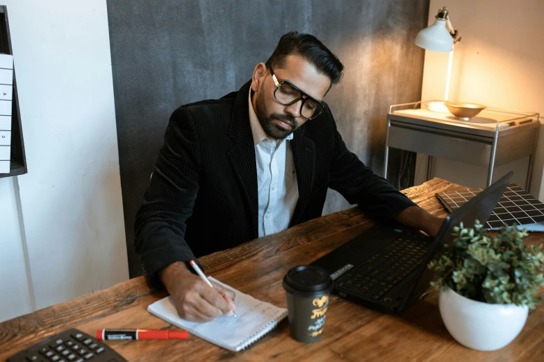 a man sitting at a desk in front of a laptop, by Robbie Trevino, pexels contest winner, hurufiyya, aboriginal australian hipster, wearing business casual dress, writing on a clipboard, thumbnail