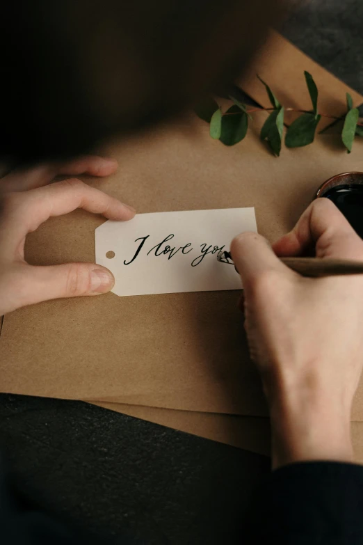 a person writing i love you on a piece of paper, pexels contest winner, romanticism, product label, diecut, tan, elegant
