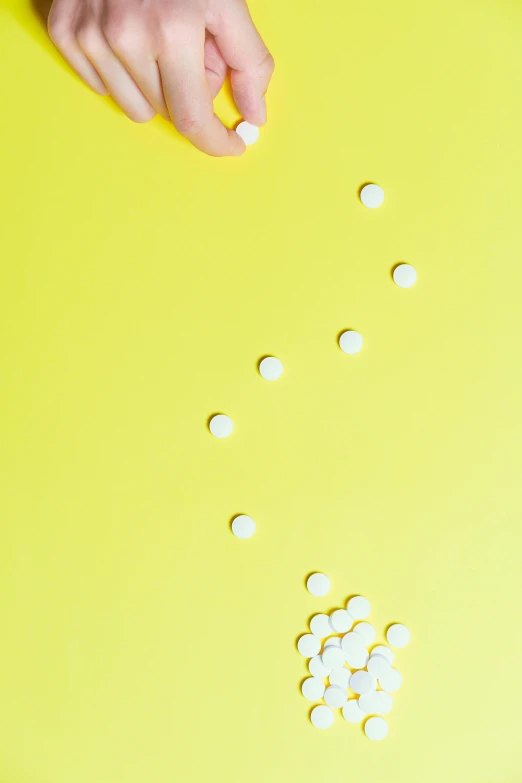 a yellow table topped with lots of white pills, trending on pexels, antipodeans, clemens ascher, synthetic skin, top down shot, 15081959 21121991 01012000 4k