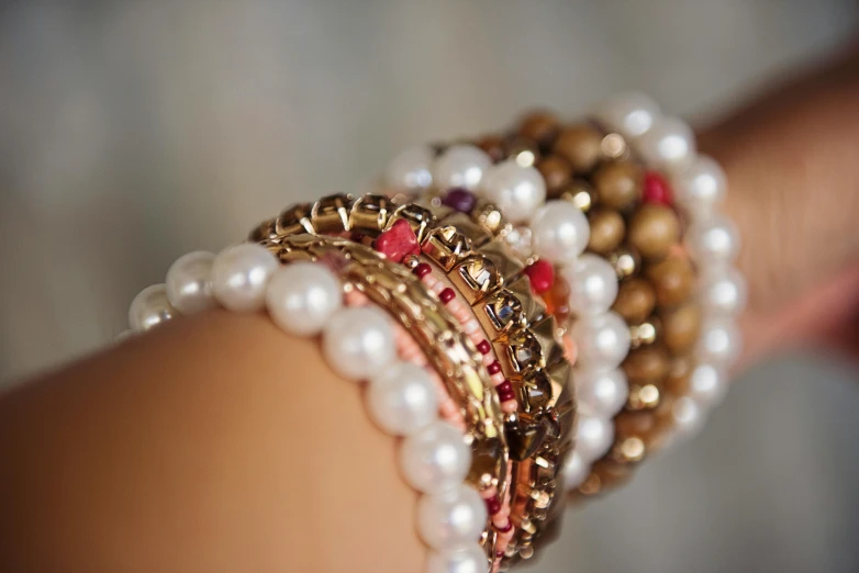 a close up of a person's arm with a bunch of bracelets on it, pexels, real pearls, red brown and white color scheme, jeweled technology, ilustration