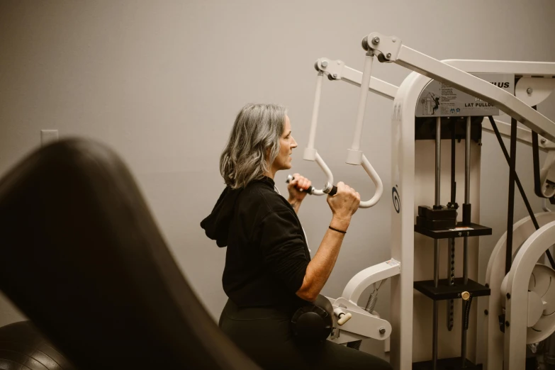 a woman is brushing her teeth in the gym, a photo, by Emma Andijewska, pexels contest winner, showing her shoulder from back, 5 5 yo, grey, background image