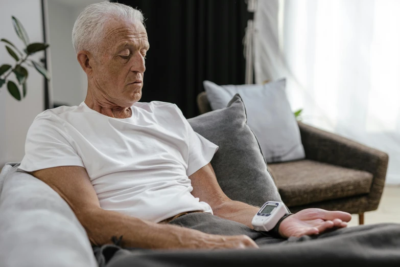 a man sitting on a couch with a remote control in his hand, pexels contest winner, hyperrealism, nursing home, heart rate, looking tired, visible veins
