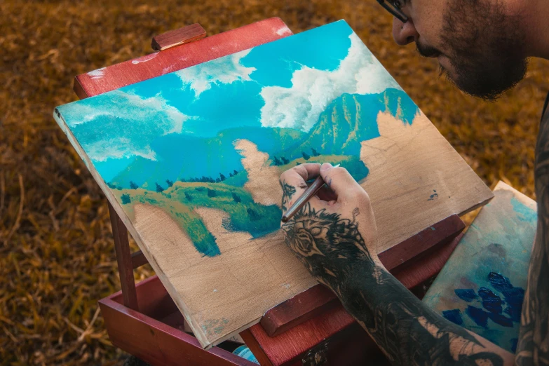 a man is painting on an easel in a field, an airbrush painting, pexels contest winner, blue paint on top, on a canva, extremely intricate