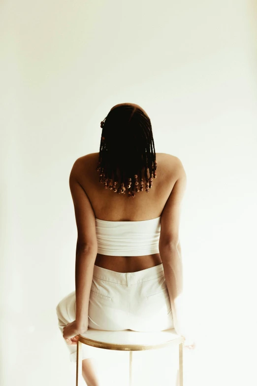 a woman in a white dress sitting on a stool, an album cover, inspired by Esaias Boursse, unsplash, bare back, crop top, early 2 0 0 0 s, dark-skinned