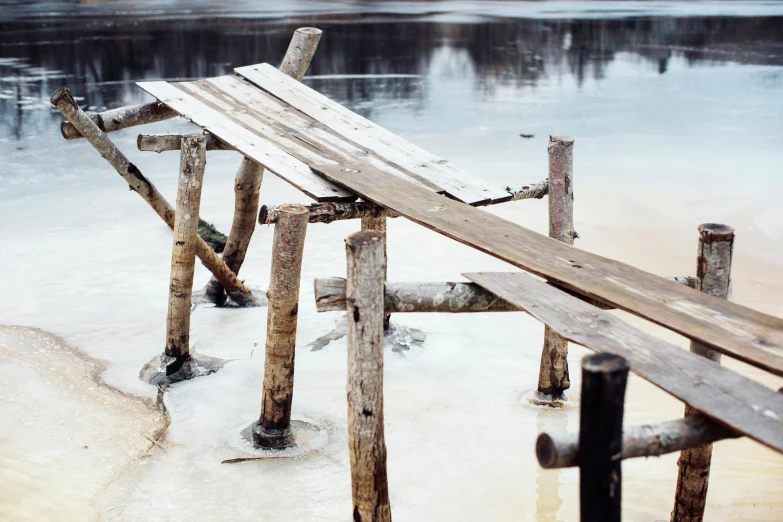 a wooden bridge over a body of water, inspired by Einar Hakonarson, pexels contest winner, land art, covered in salt, old furnitures, grey, (3 are winter