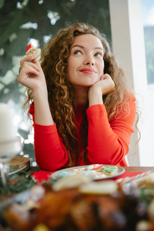 a woman sitting at a table with a plate of food, holiday vibe, teen elf, profile image, curly haired