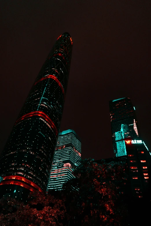 a couple of tall buildings lit up at night, inspired by Cheng Jiasui, pexels contest winner, hypermodernism, green and red, low quality photo, 2022 photograph, buildings covered in black tar