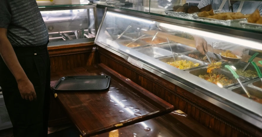 a man standing in front of a buffet filled with food, completely empty, freezing, at the counter, sunken