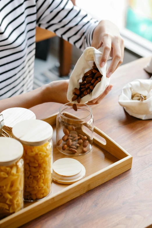 a woman sitting at a table with a tray of food, pexels contest winner, process art, picking up a can beans, inside a glass jar, pouches, sleek design