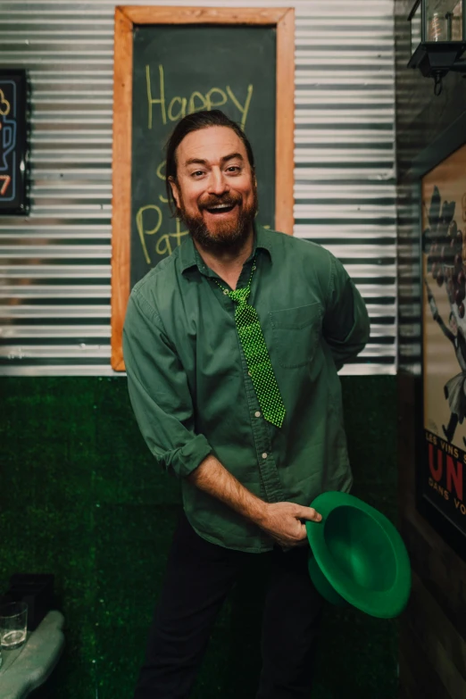 a man in a green shirt and tie holding a green hat, standup comedian, timothy rees, green snakes, ari aster