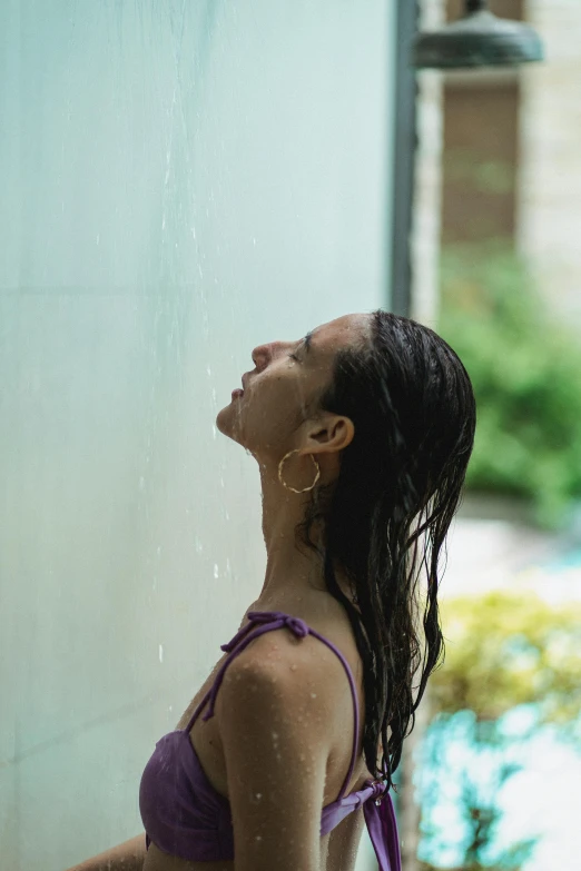 a woman in a purple bikini standing in a shower, pexels contest winner, right side profile, lush surroundings, rain on screen, wellness pool