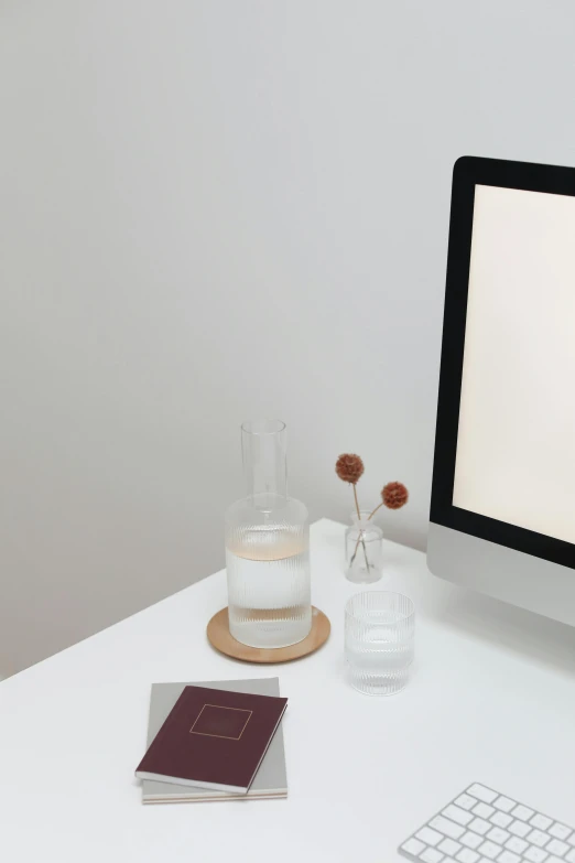 a computer monitor sitting on top of a white desk, by Carey Morris, minimalism, in a short round glass vase, filling with water, glowing aesthetic, matte white background