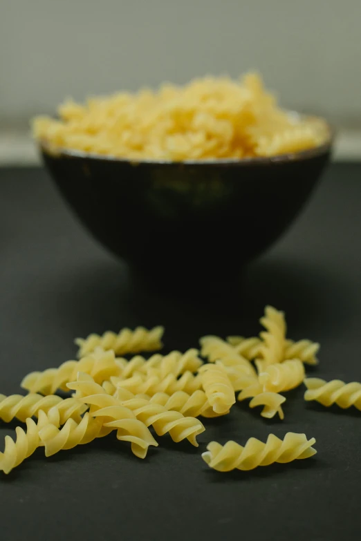 a black bowl filled with pasta on top of a table, grain, spiky, college, high quality product image”