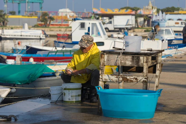 a man sitting on a dock next to a bunch of boats, by Julia Pishtar, mediterranean fisher village, maintenance photo, as well as the handyboy, thumbnail