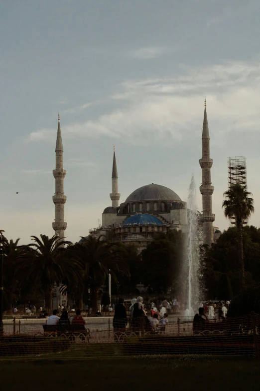 a large building with a fountain in front of it, an album cover, inspired by Altoon Sultan, pexels contest winner, hurufiyya, black domes and spires, panorama view, sunfaded, blue skies