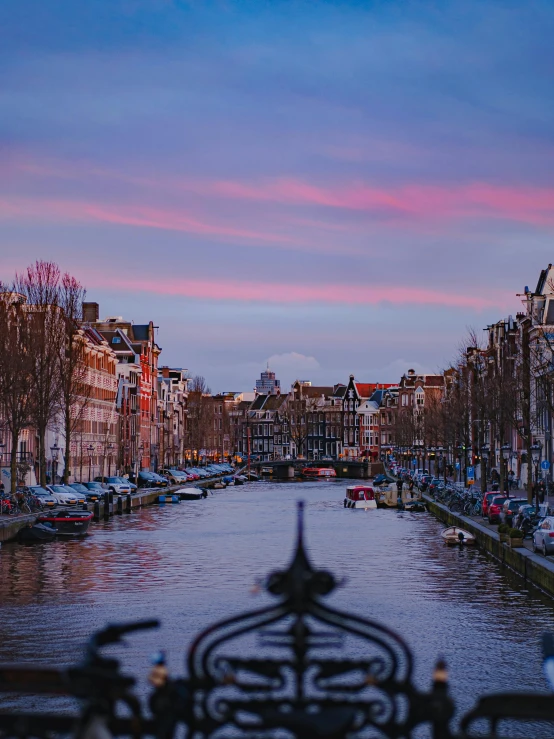 a river running through a city next to tall buildings, by Jonas De Ro, pexels contest winner, pink skies, view of houses in amsterdam, 🚿🗝📝, prussian blue and venetian red