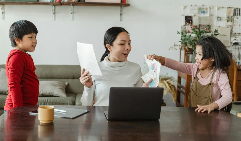 a woman and two children sitting at a table with a laptop, a cartoon, pexels contest winner, happening, throwing cards in the air, asian woman made from origami, cash on a sidetable, document photo