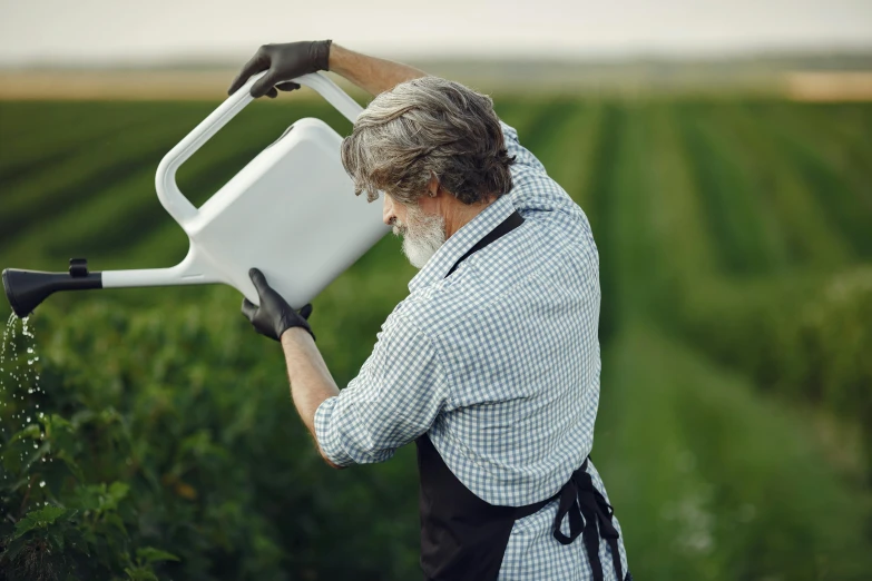 a man holding a watering can in a field, official product photo, white apron, thumbnail, hydroponic farms