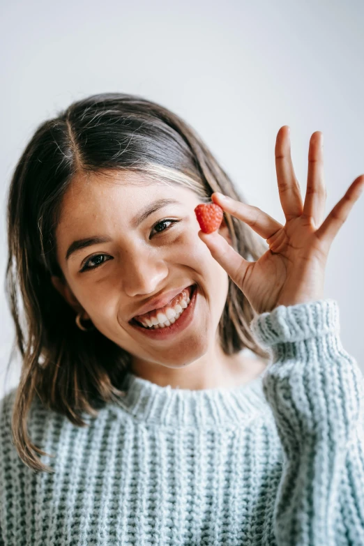 a woman making a peace sign with her hands, pexels contest winner, fight with strawberries, portrait sophie mudd, detailed smile, smol