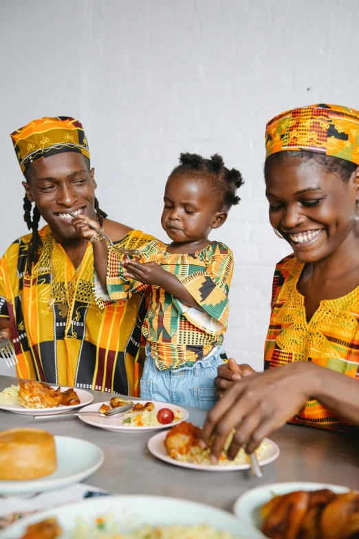 a group of people sitting at a table with plates of food, inspired by Ras Akyem, pexels contest winner, black arts movement, portrait of family of three, wearing authentic attire, reggae, promotional image