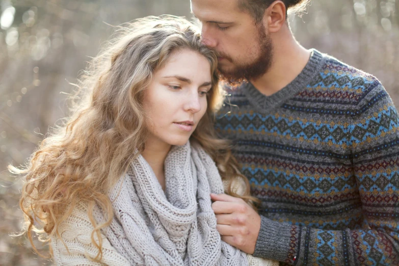 a man and a woman standing next to each other, trending on pexels, romanticism, wearing sweater, wind in hair, beautiful nordic woman, comforting