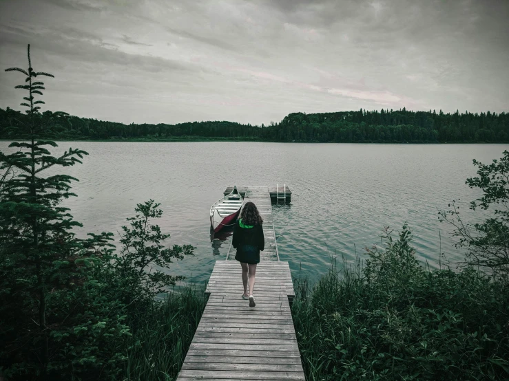 a person standing on a dock near a body of water, inspired by Elsa Bleda, pexels contest winner, happening, cottagecore, canoe, grey, a woman walking