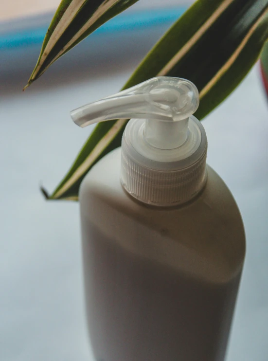 a bottle of lotion sitting on a table next to a plant, a picture, unsplash, plasticien, prosthetic arm, brown, graying hair, silicone skin