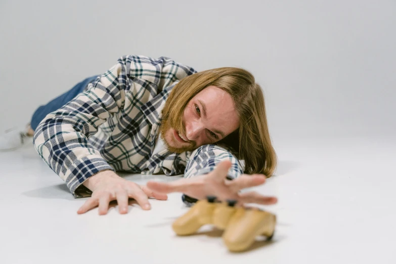 a woman laying on the floor next to a pair of shoes, inspired by Sarah Lucas, unsplash, a sad cheese puppet, ricky berwick, holding his hands up to his face, holding controller