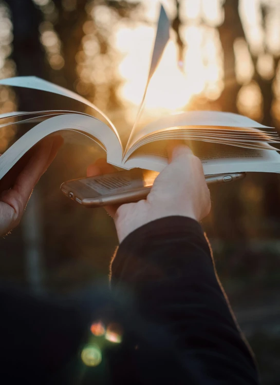 a person holding an open book in their hands, by Niko Henrichon, trending on unsplash, happening, golden hour cinematic, avatar image, phone photo, large)}]