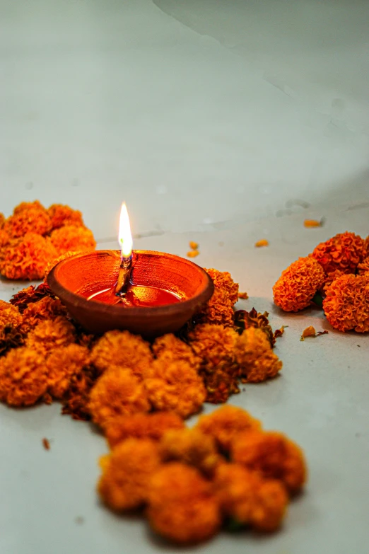 a lit candle sitting on top of a pile of flowers, hurufiyya, kali, orange flowers, multiple lights, at home