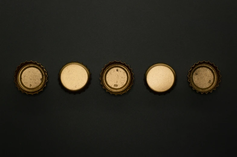 a group of four bottle caps sitting on top of a table, digital art, unsplash, visual art, gold inlay, ignant, brown, plain