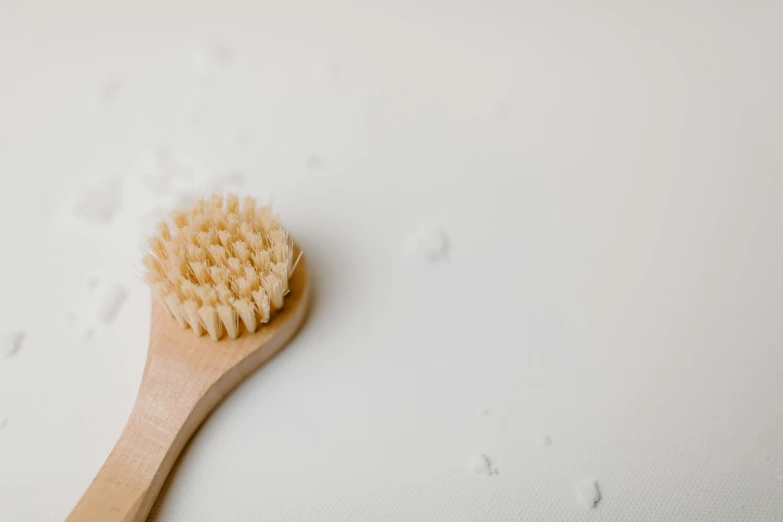 a wooden brush sitting on top of a white surface, unsplash, bubble bath, background image, spikes on the body, partially covered with dust