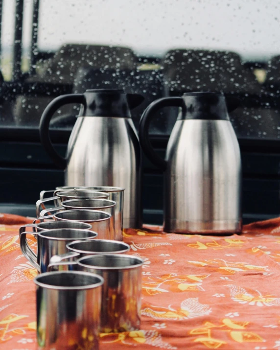 a group of cups sitting on top of a table, stainless steel, road trip, official product photo, pouring