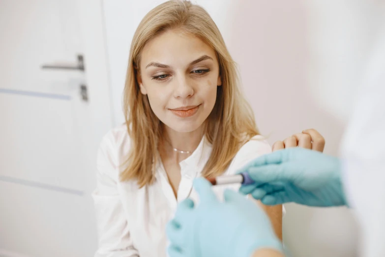 a woman getting her teeth examined by a doctor, by Matija Jama, trending on pexels, holding a syringe, angelina stroganova, looking from shoulder, thumbnail