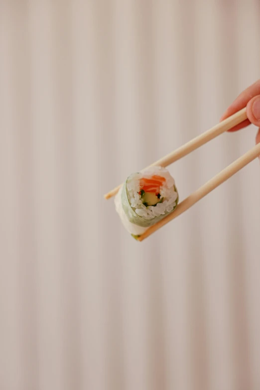 a person holding chopsticks over a piece of sushi, inspired by Maki Haku, unsplash, pastel green, square, b - roll, made of bamboo