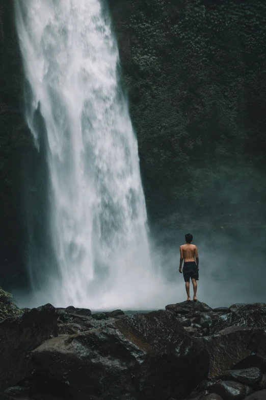 a man standing in front of a waterfall, pexels contest winner, bali, facing away, max dennison, ignant