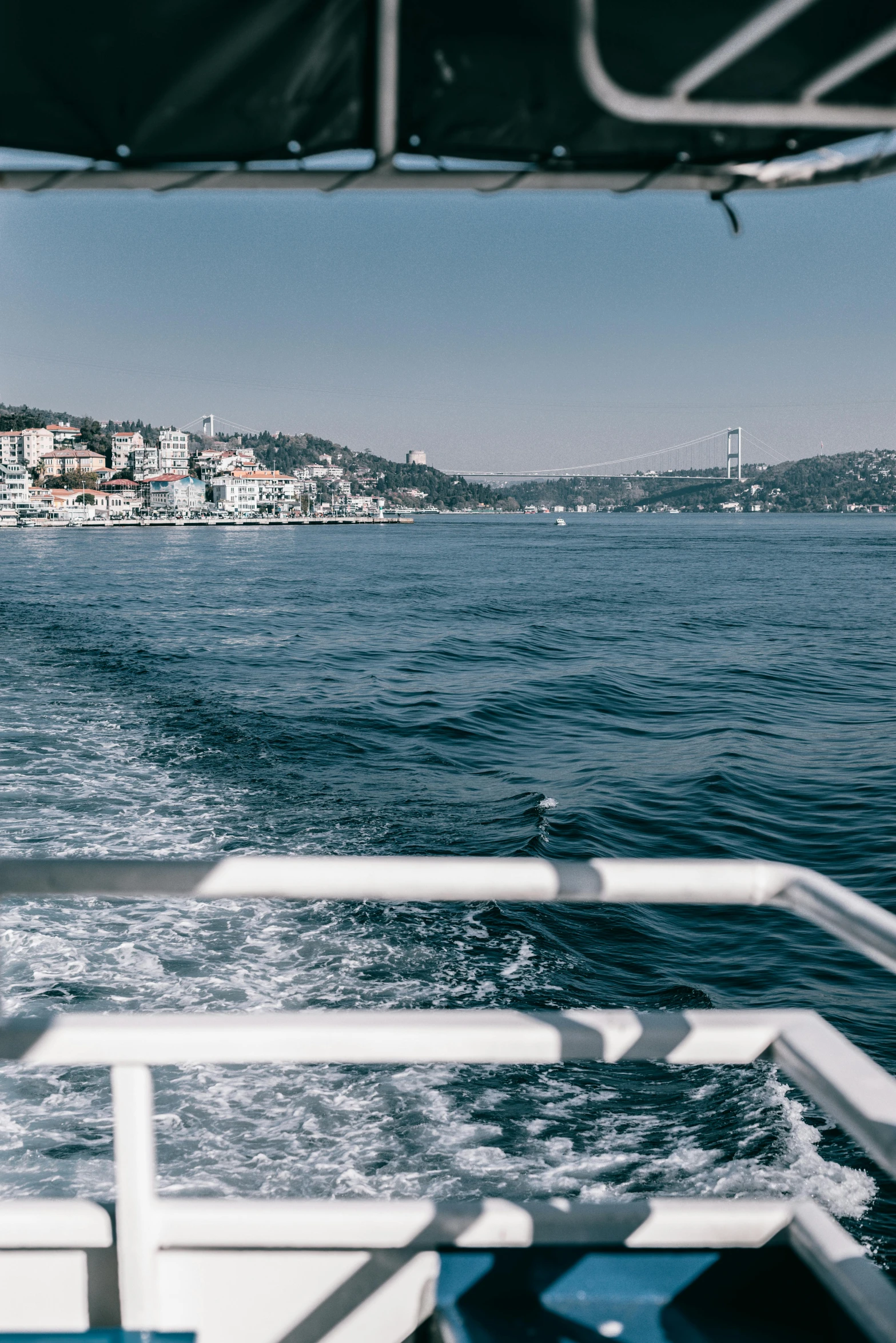 a view of a city from the back of a boat, by Niyazi Selimoglu, color image, crystal clear blue water, 2022 photograph, muted color (blues