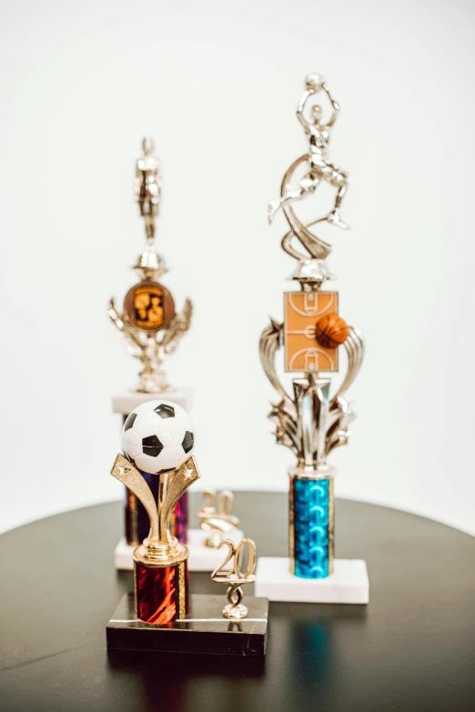 a couple of trophies sitting on top of a table, glitter accents on figure, soccer, jewelry, various colors