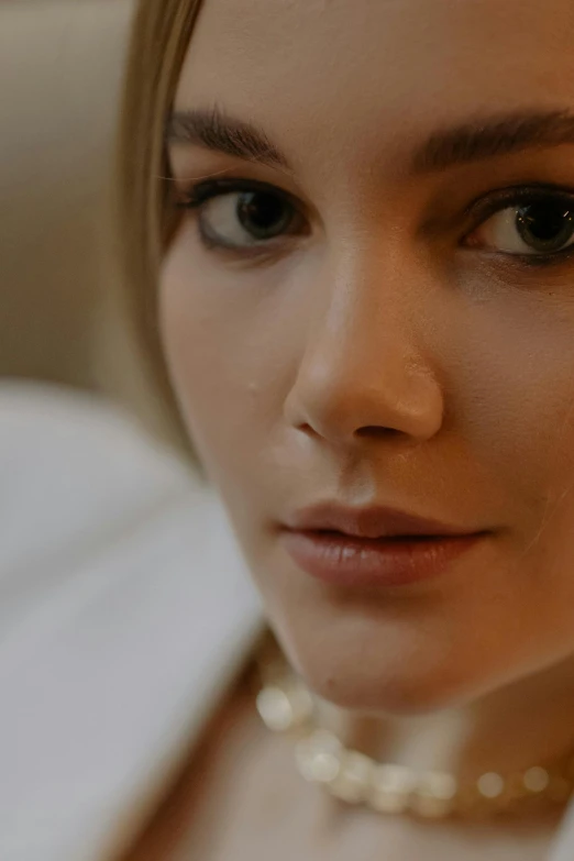 a close up of a woman wearing a pearl necklace, shot on anamorphic lenses, robe. perfect face, uhd face details, sydney sweeney