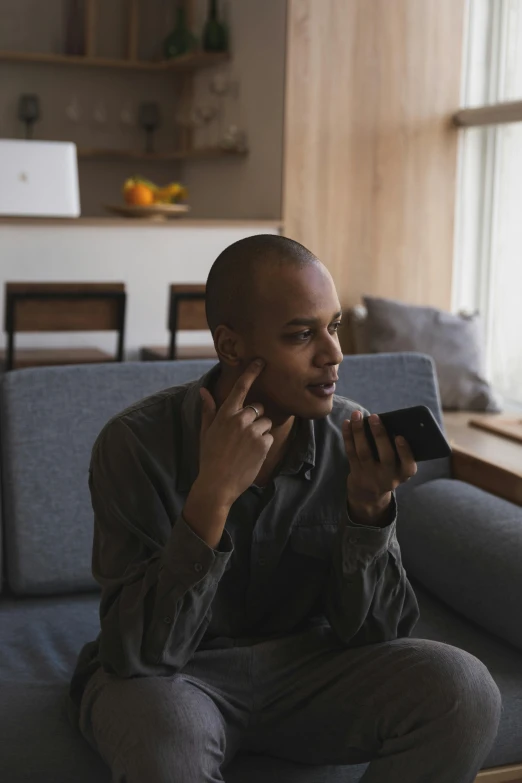 a man sitting on a couch talking on a cell phone, trending on pexels, non-binary, ashteroth, sitting on man's fingertip, shaven