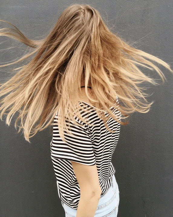 a woman with her hair blowing in the wind, trending on unsplash, striped shirt, brunette with dyed blonde hair, low quality photo, instagram post