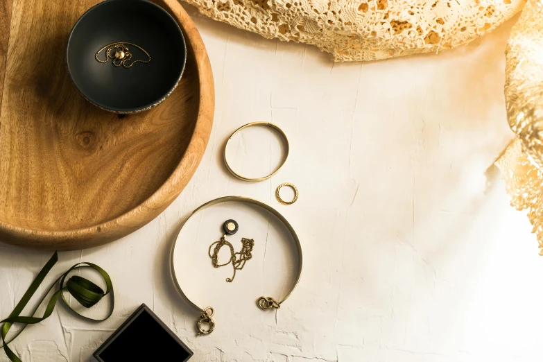 a wooden tray sitting on top of a white table, a still life, by Julia Pishtar, trending on pexels, metal neck rings, gold and black, various posed, detailed product image