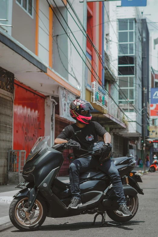 a man riding on the back of a motorcycle down a street, wearing all black mempo mask, malaysian, custom scooter, contemplating