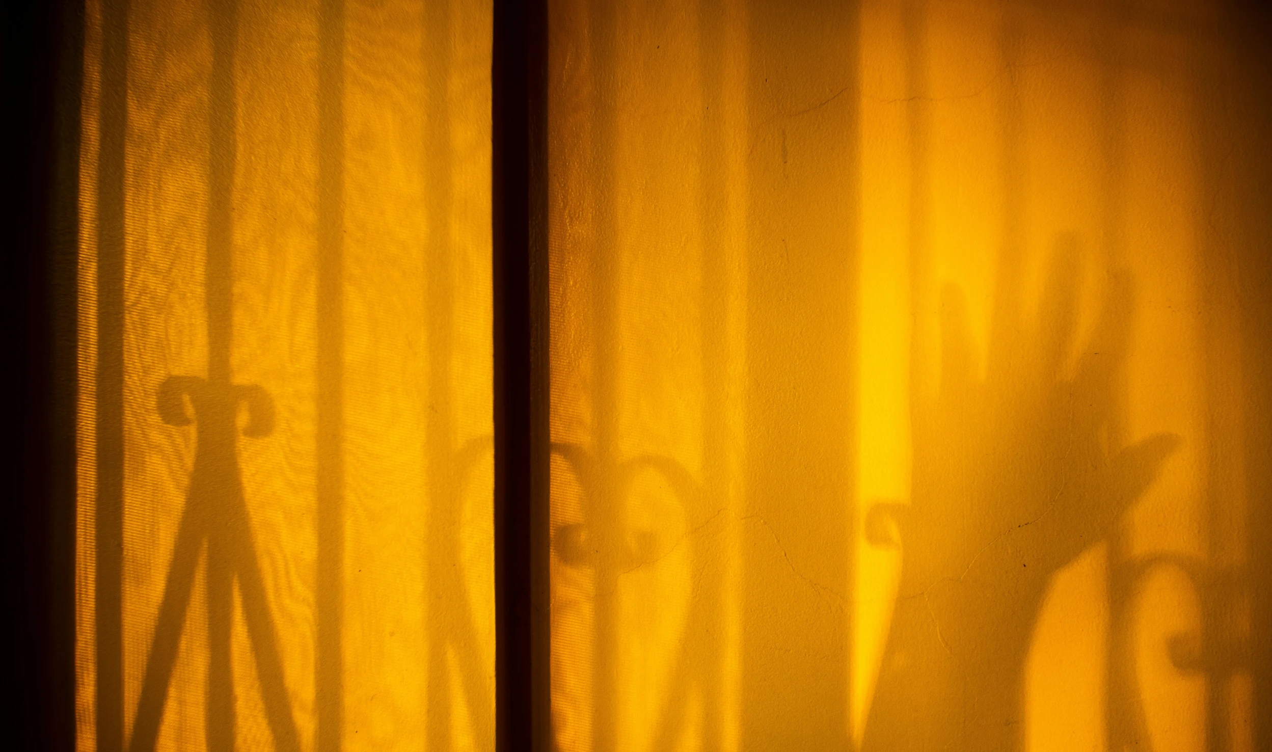 a shadow of a person behind a curtain, inspired by Brassaï, lyrical abstraction, yellow lanterns, golden hour hues, behind bars, orange yellow