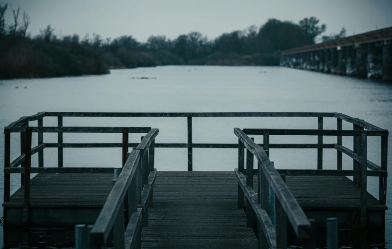 a wooden dock next to a body of water, unsplash, happening, grey, winter photograph, multiple stories, looking threatening