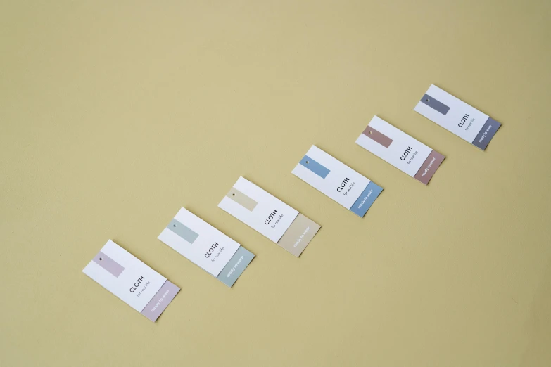 a row of business cards sitting on top of a table, inspired by Giorgio Morandi, color field, product label, grey, obelisks, complimentary colours