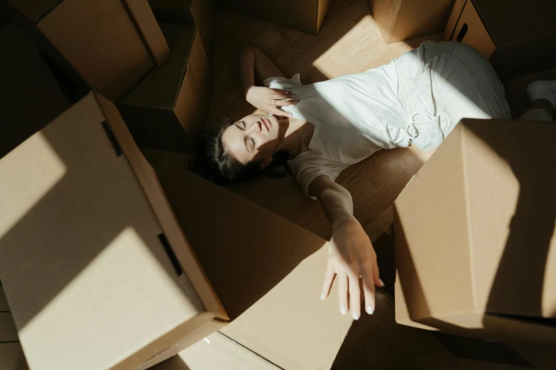 a woman laying on top of a cardboard box, by Emma Andijewska, pexels contest winner, renaissance, avatar image, collapsed floors, multiple stories, movie still of a tired