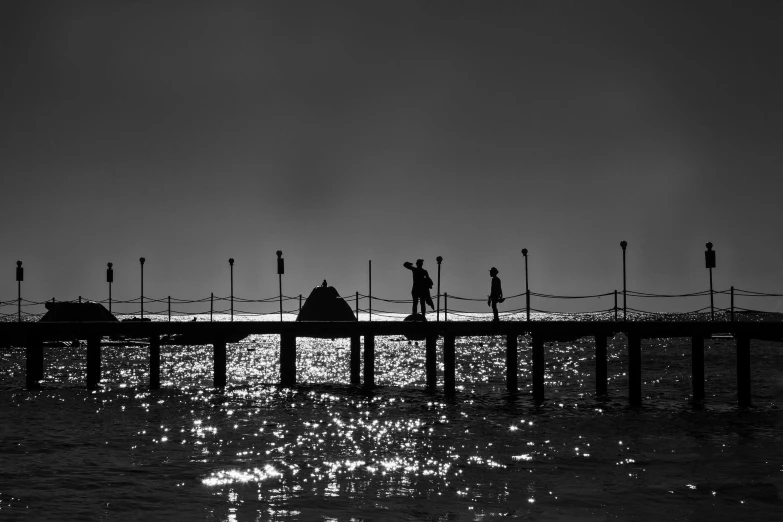 a black and white photo of people on a pier, by Tamas Galambos, pexels contest winner, romanticism, backlit!!, fishing, seaside, (high contrast)